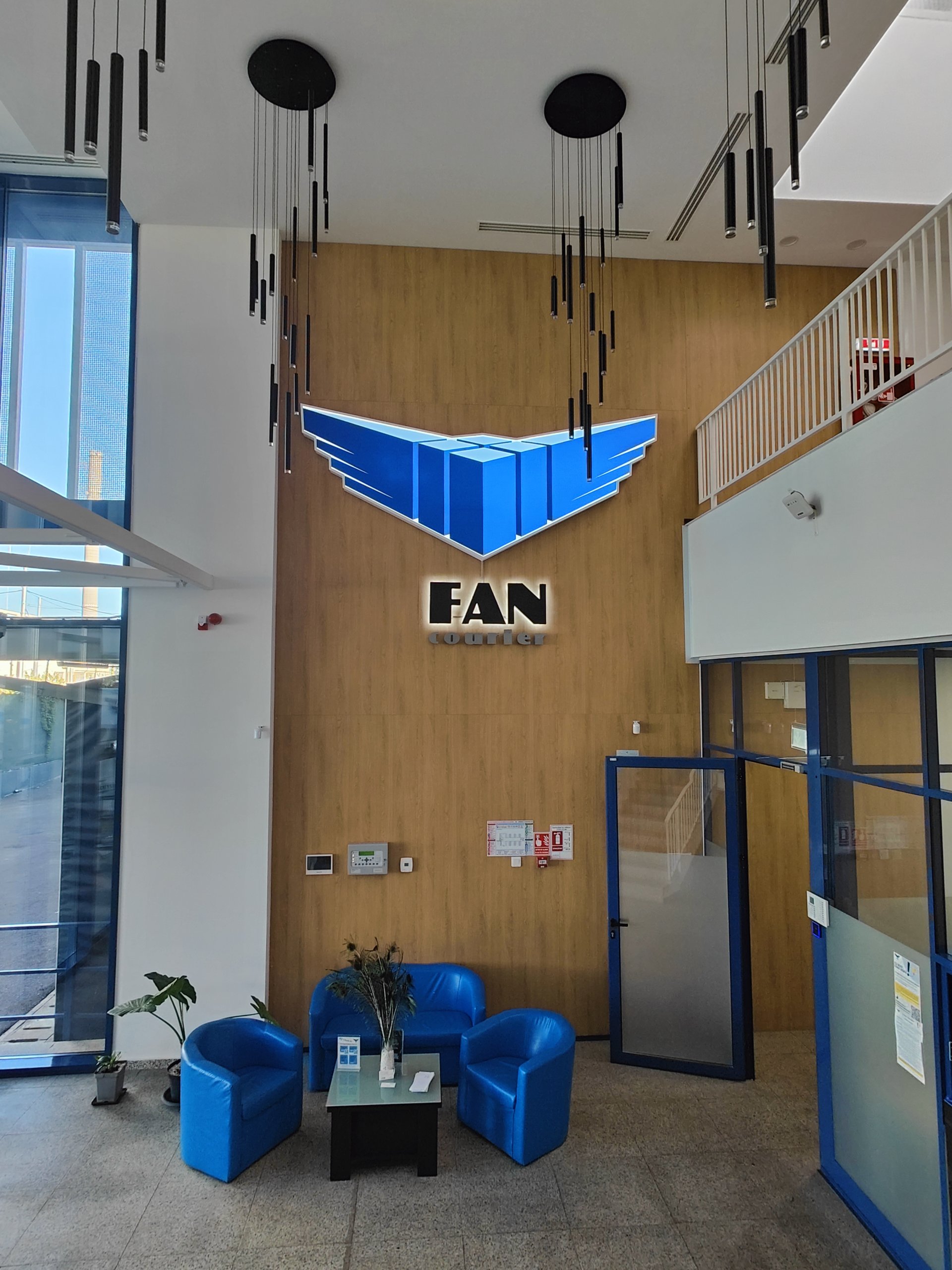 Lobby clădire de birouri hub FAN Courier str. Acțiunii cu logo brand pe placaj de lemn și mobilier albastru, proiect PPAE