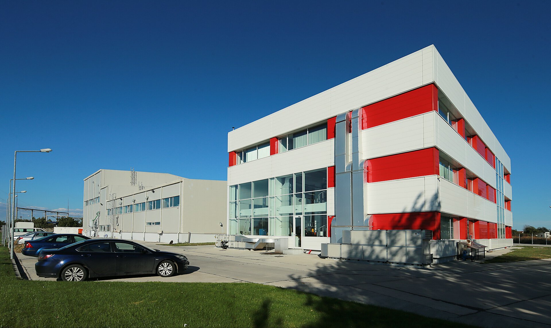 Overall view of Romcolor Copaceni with the administrative building with white-red facade and the adjacent production hall, PPAE project